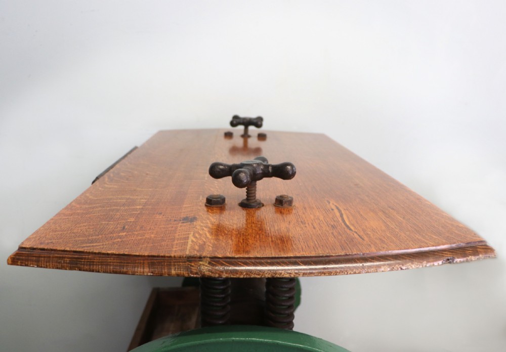An antique Victorian cast iron mangle with a green and red painted frame, wooden wringer rollers, and a wood tabletop. View XIII