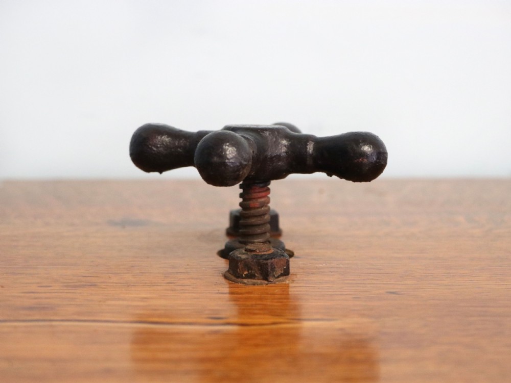 An antique Victorian cast iron mangle with a green and red painted frame, wooden wringer rollers, and a wood tabletop. View XVI