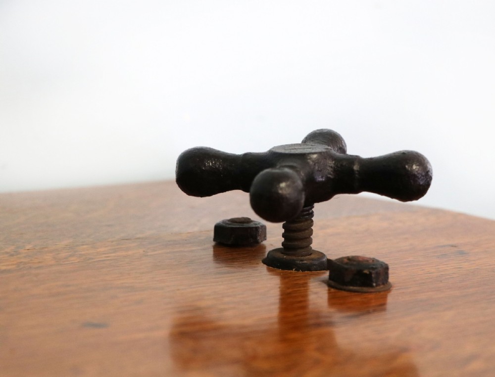 An antique Victorian cast iron mangle with a green and red painted frame, wooden wringer rollers, and a wood tabletop. View XVII