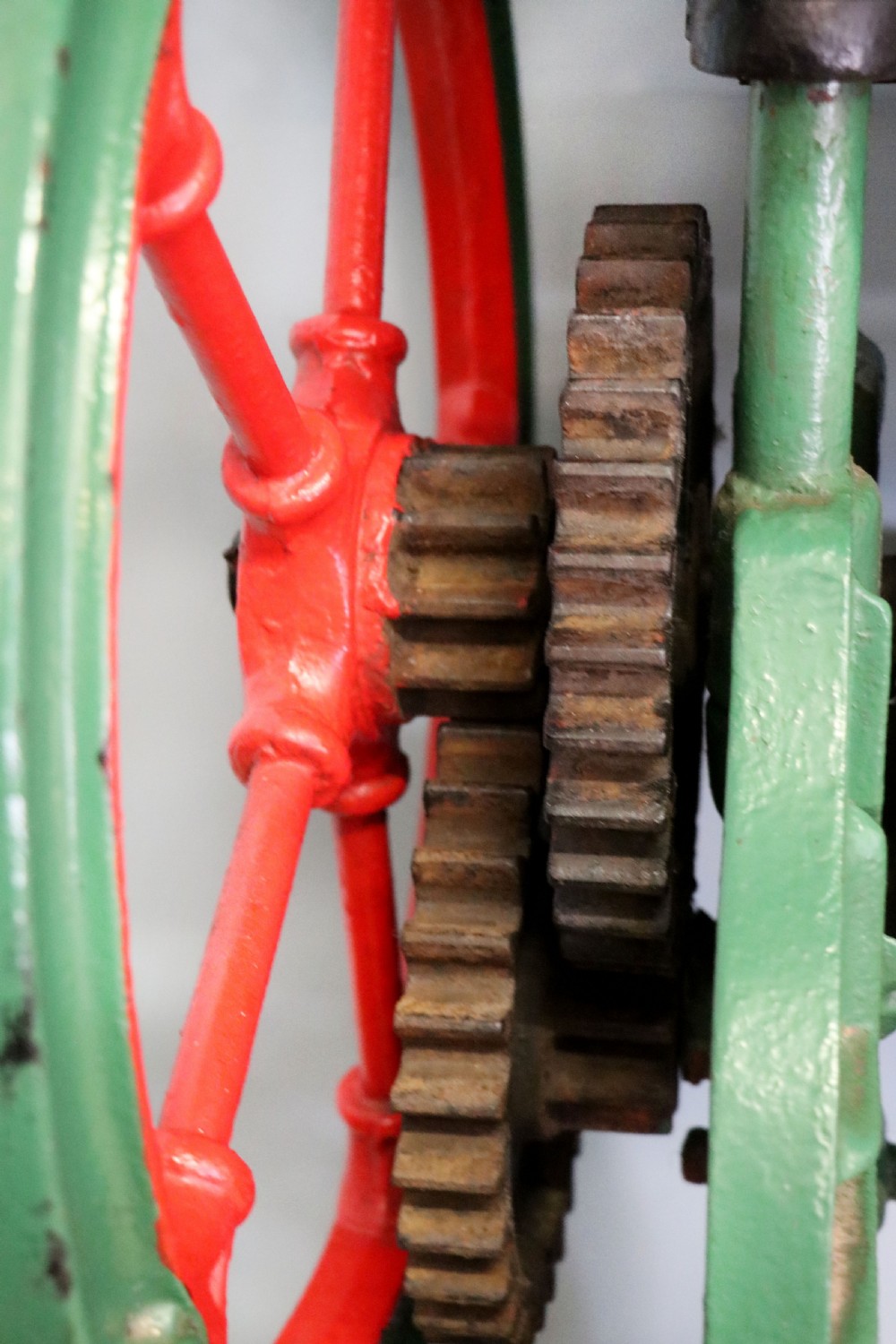 An antique Victorian cast iron mangle with a green and red painted frame, wooden wringer rollers, and a wood tabletop. View XXII