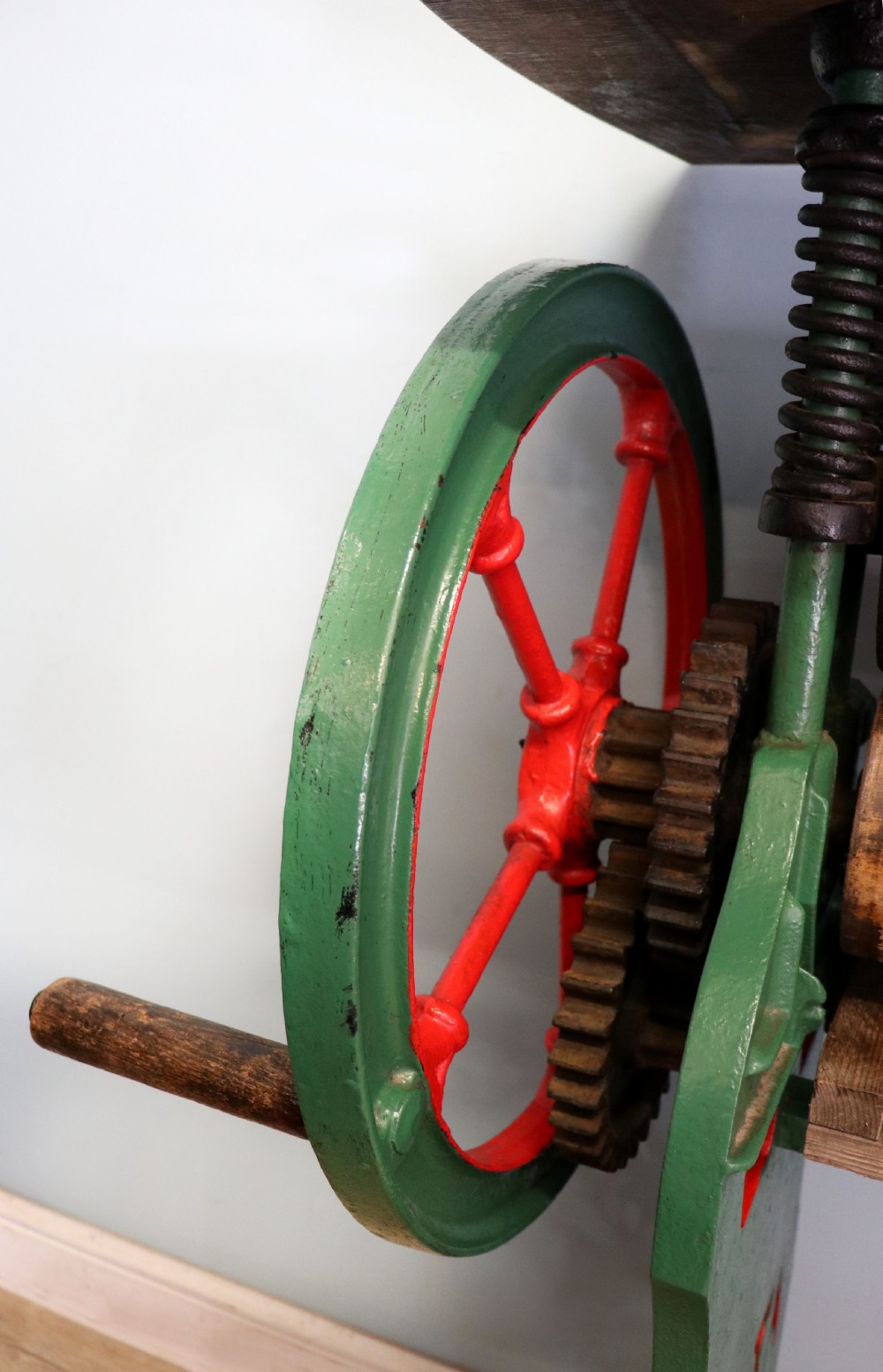 An antique Victorian cast iron mangle with a green and red painted frame, wooden wringer rollers, and a wood tabletop. View XXIII