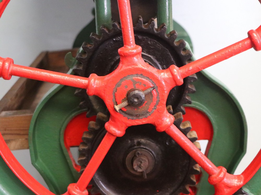 An antique Victorian cast iron mangle with a green and red painted frame, wooden wringer rollers, and a wood tabletop. View XXV