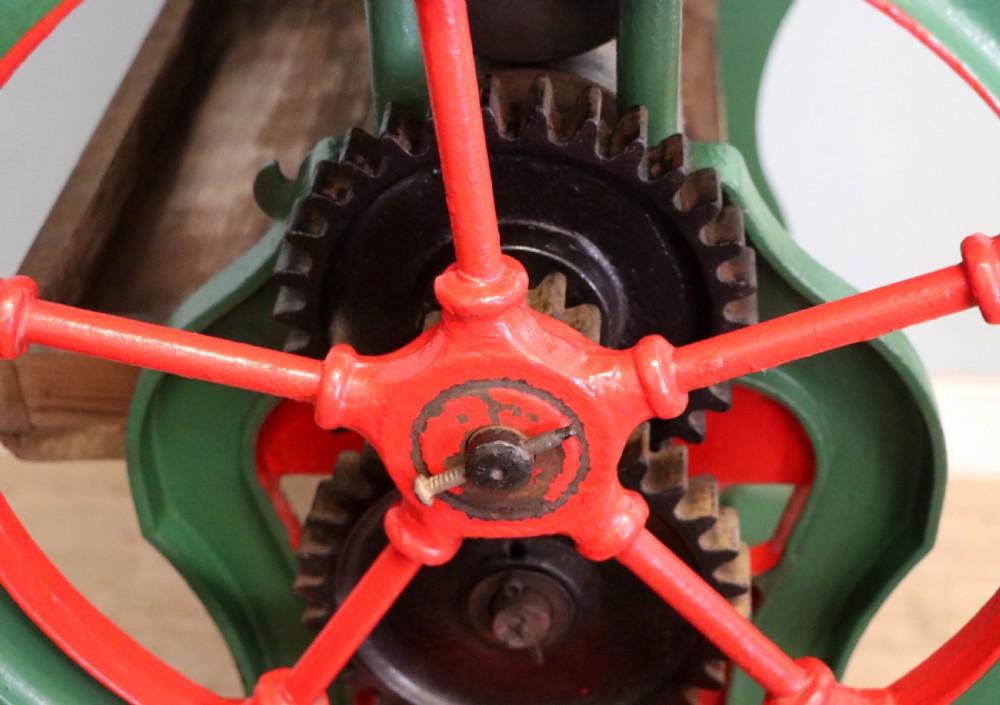 An antique Victorian cast iron mangle with a green and red painted frame, wooden wringer rollers, and a wood tabletop. View XXVII