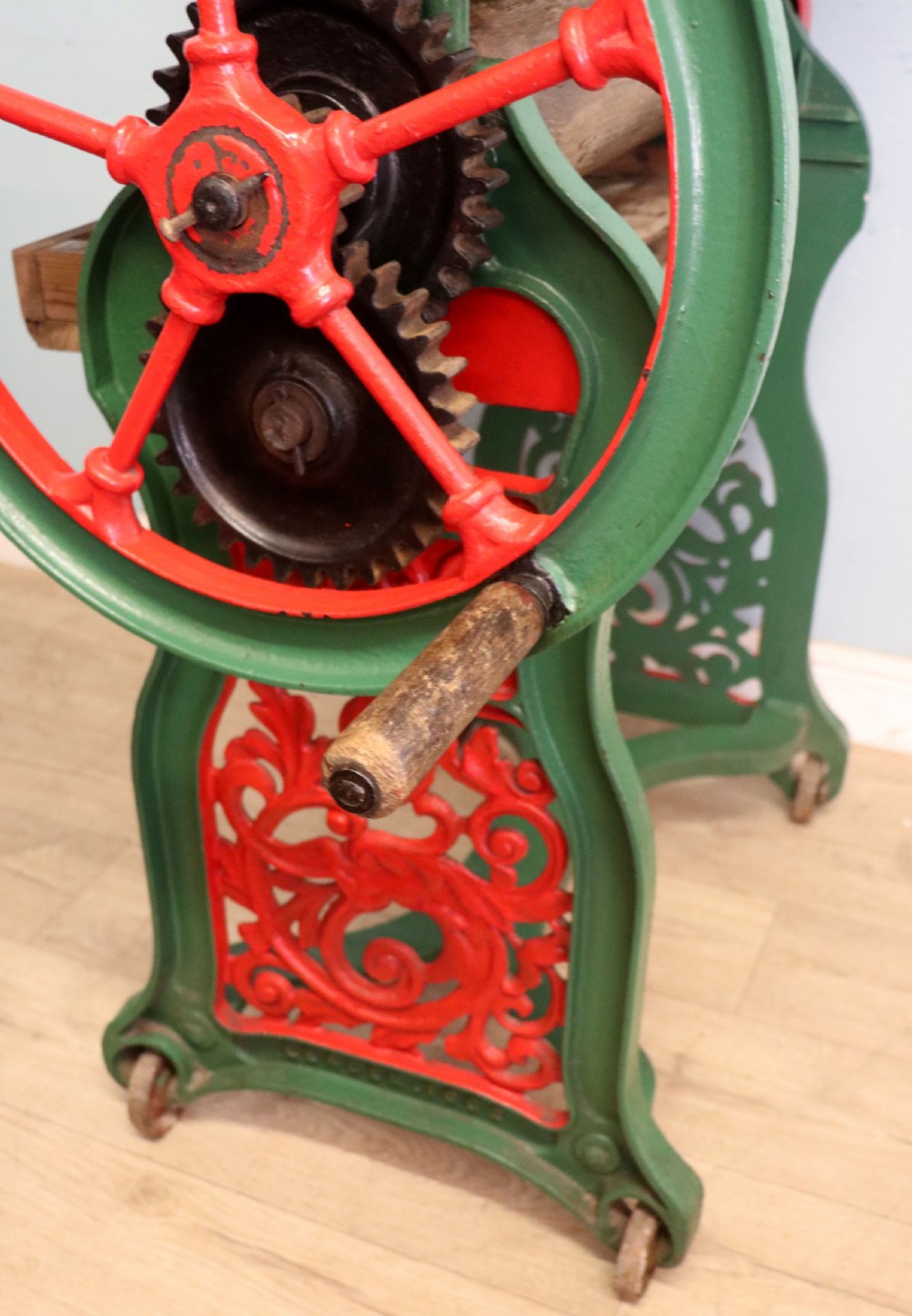 An antique Victorian cast iron mangle with a green and red painted frame, wooden wringer rollers, and a wood tabletop. View XXIX