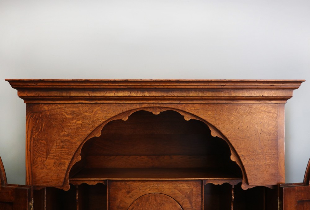 A Georgian style warm brown oak bureau cabinet featuring two upper arched doors opening to a fitted interior of pigeonholes and small drawers above three long drawers with brass handles. View XI