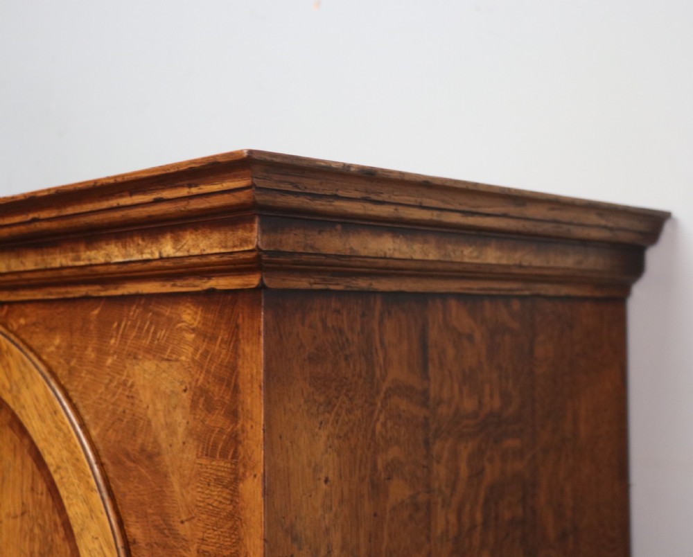 A Georgian style warm brown oak bureau cabinet featuring two upper arched doors opening to a fitted interior of pigeonholes and small drawers above three long drawers with brass handles. View XII
