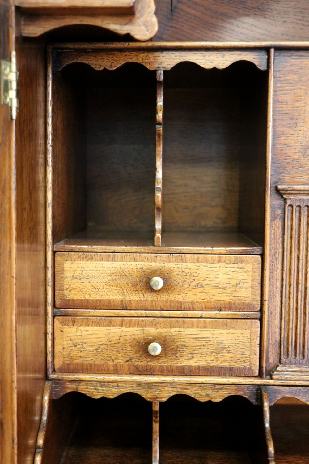 A Georgian style warm brown oak bureau cabinet featuring two upper arched doors opening to a fitted interior of pigeonholes and small drawers above three long drawers with brass handles. View XVIII