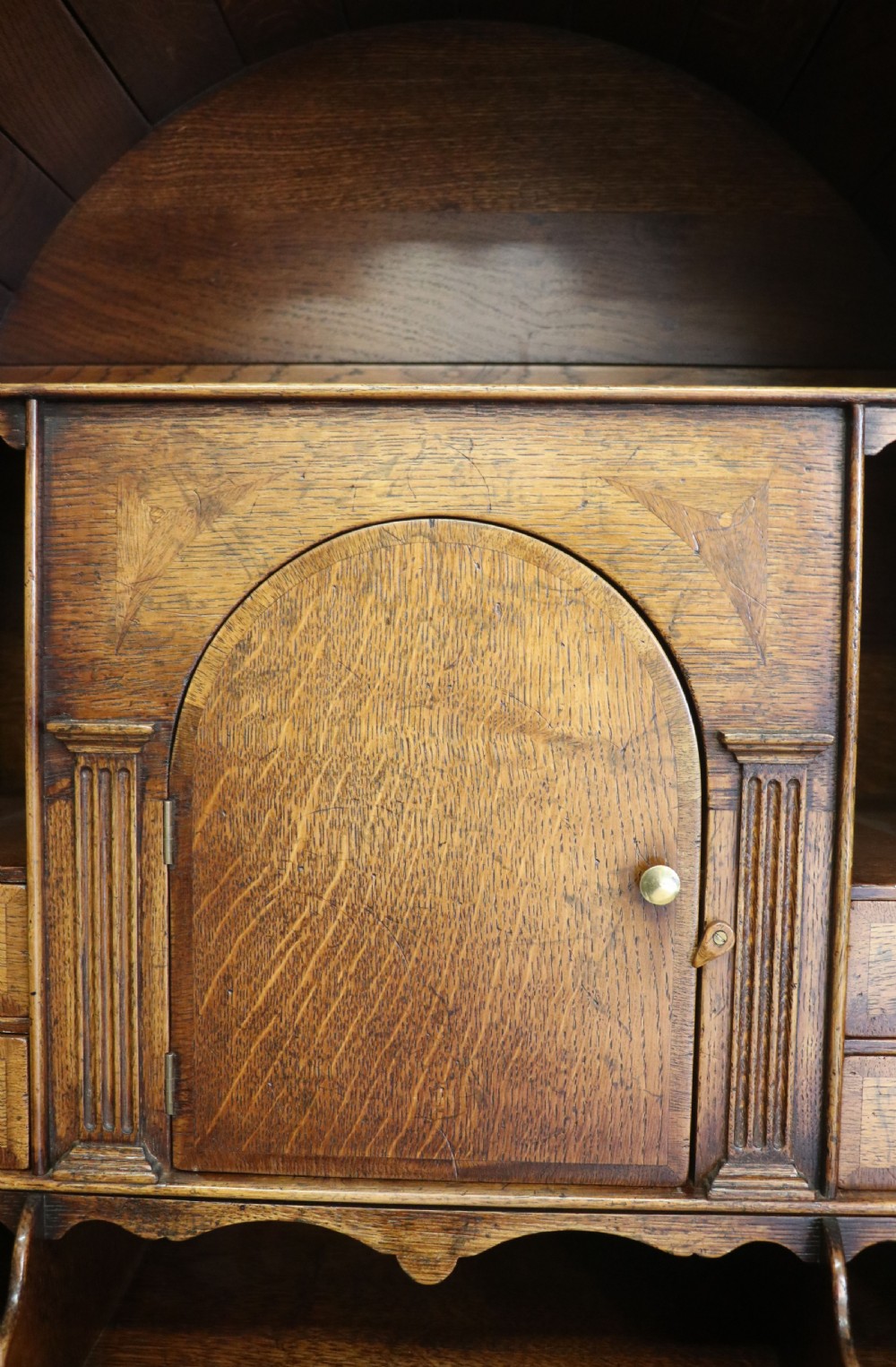 A Georgian style warm brown oak bureau cabinet featuring two upper arched doors opening to a fitted interior of pigeonholes and small drawers above three long drawers with brass handles. View XIX