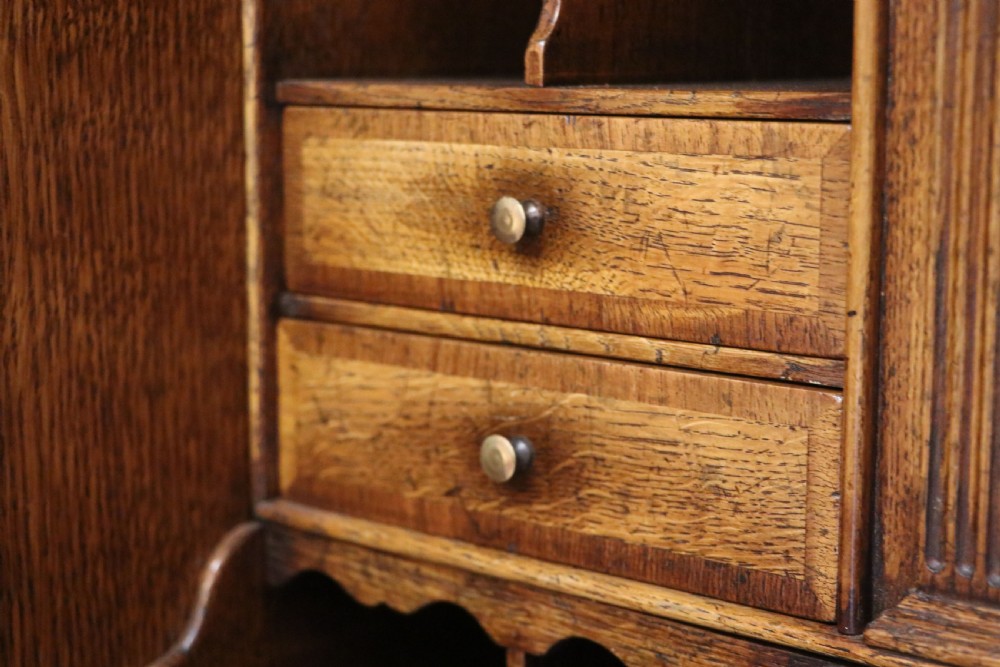 A Georgian style warm brown oak bureau cabinet featuring two upper arched doors opening to a fitted interior of pigeonholes and small drawers above three long drawers with brass handles. View XXII