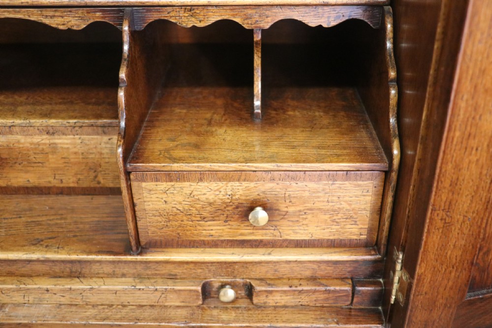 A Georgian style warm brown oak bureau cabinet featuring two upper arched doors opening to a fitted interior of pigeonholes and small drawers above three long drawers with brass handles. View XXIII