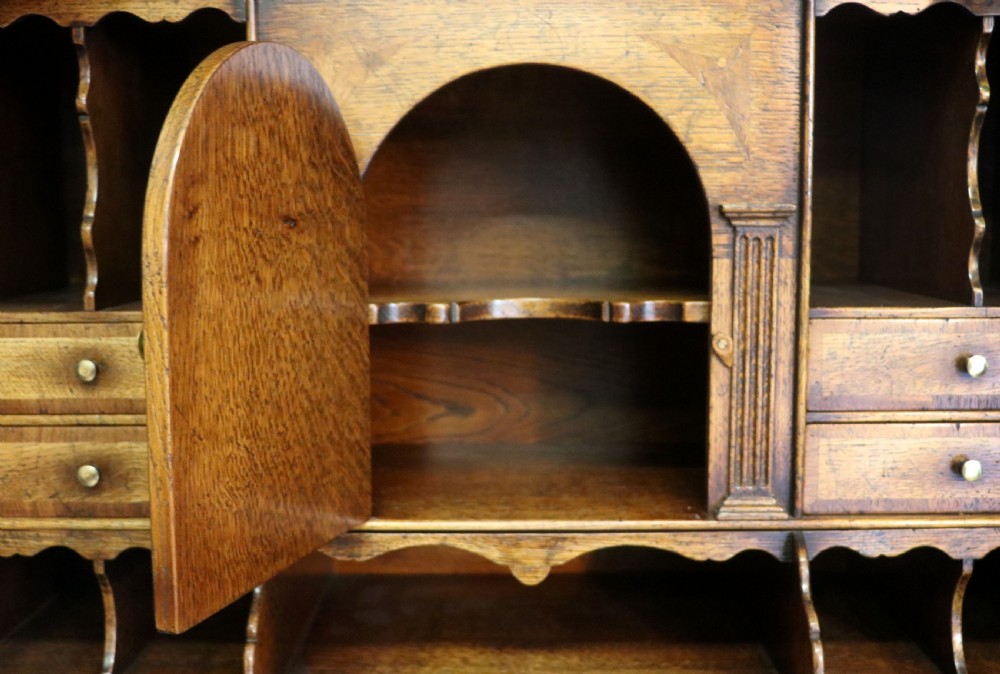 A Georgian style warm brown oak bureau cabinet featuring two upper arched doors opening to a fitted interior of pigeonholes and small drawers above three long drawers with brass handles. View XXIV