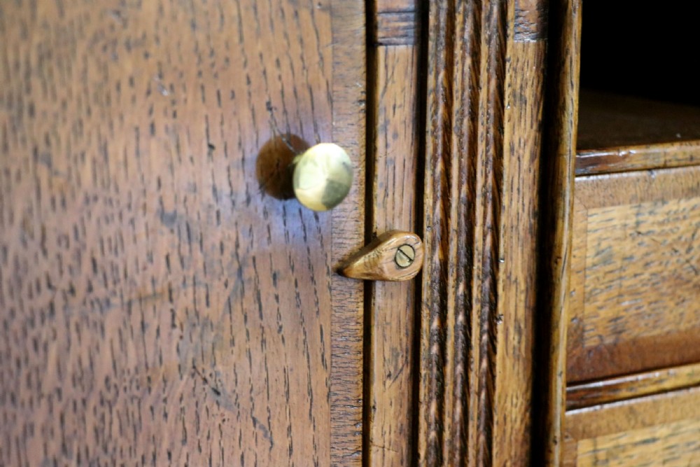 A Georgian style warm brown oak bureau cabinet featuring two upper arched doors opening to a fitted interior of pigeonholes and small drawers above three long drawers with brass handles. View XXVII
