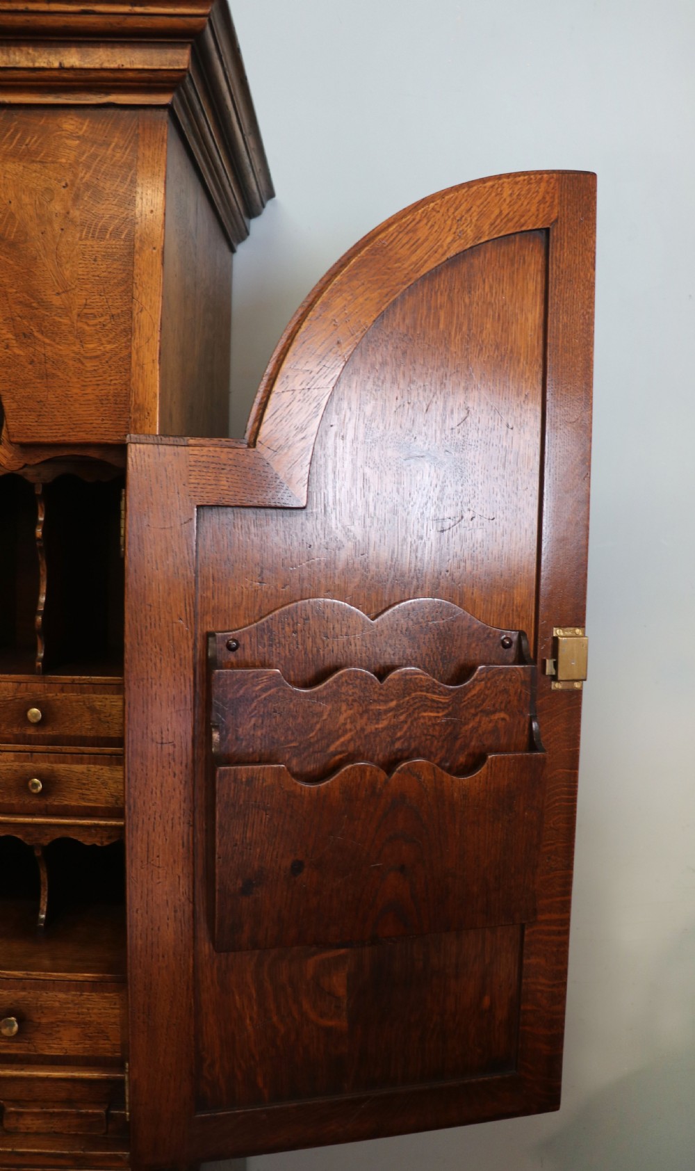 A Georgian style warm brown oak bureau cabinet featuring two upper arched doors opening to a fitted interior of pigeonholes and small drawers above three long drawers with brass handles. View XXIX