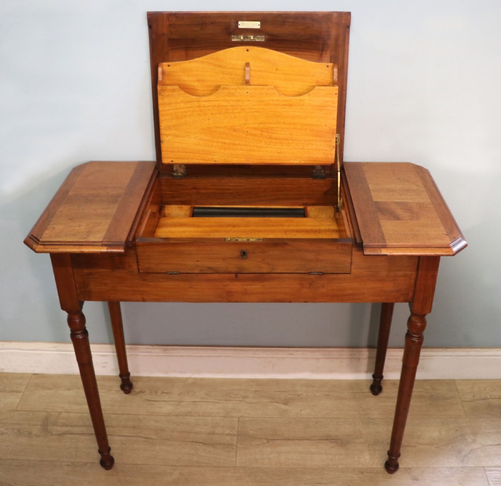A brown walnut metamorphic writing desk featuring turned legs, side flaps, and an open top section exposing internal stationery compartments. View II