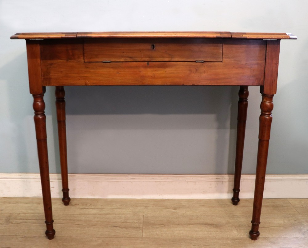 A brown walnut metamorphic writing desk featuring turned legs, side flaps, and an open top section exposing internal stationery compartments. View IV