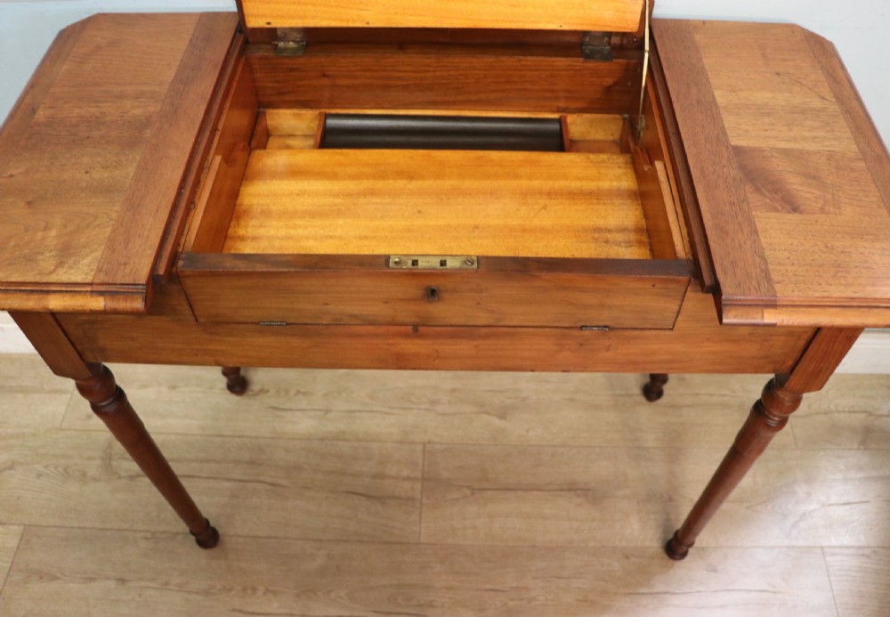 A brown walnut metamorphic writing desk featuring turned legs, side flaps, and an open top section exposing internal stationery compartments. View XV