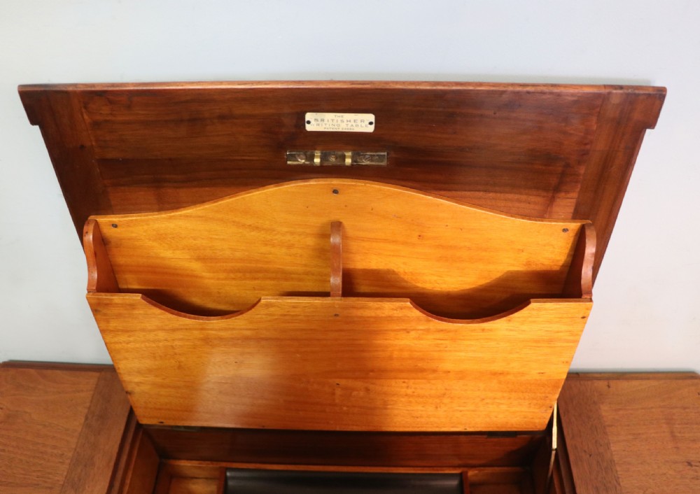 A brown walnut metamorphic writing desk featuring turned legs, side flaps, and an open top section exposing internal stationery compartments. View XX
