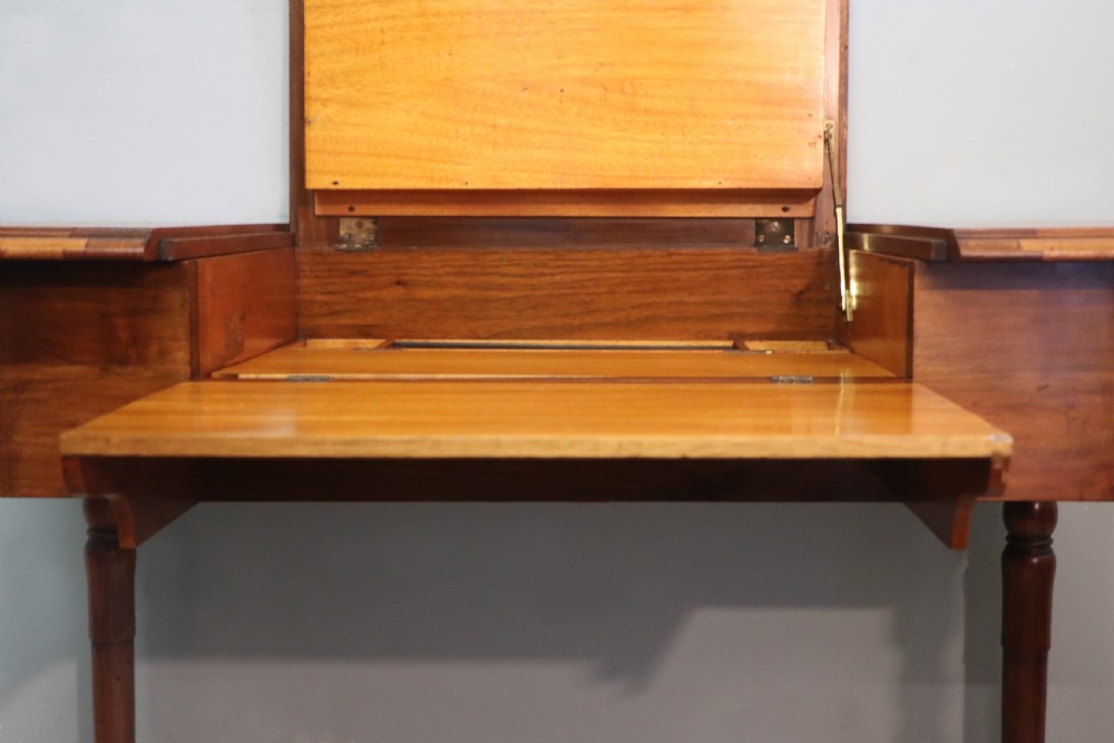 A brown walnut metamorphic writing desk featuring turned legs, side flaps, and an open top section exposing internal stationery compartments. View XXI