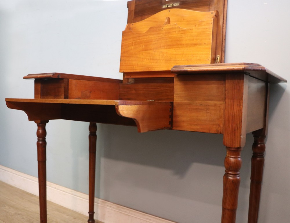 A brown walnut metamorphic writing desk featuring turned legs, side flaps, and an open top section exposing internal stationery compartments. View XXIX