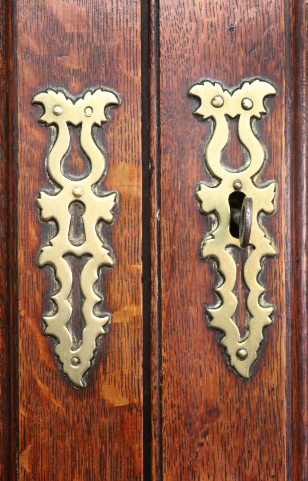 A George III oak bureau bookcase featuring a dentil cornice above two panelled upper doors, a slant-front writing slope opening to a fitted interior, and three long drawers below with brass handles. View XXIV