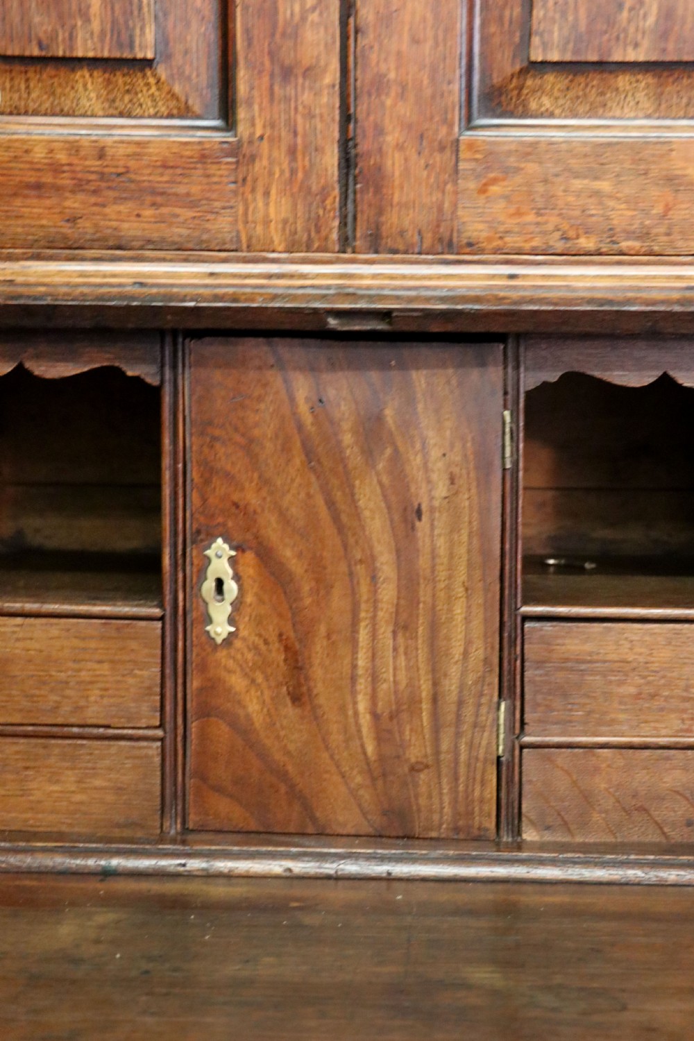 A George III oak bureau bookcase featuring a dentil cornice above two panelled upper doors, a slant-front writing slope opening to a fitted interior, and three long drawers below with brass handles. View XXX