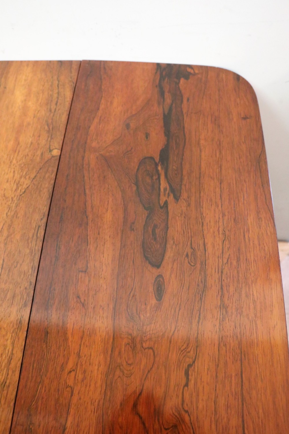 A late Georgian drop-leaf sofa table crafted from dark figured rosewood with a turned pedestal stem, two frieze drawers, and splayed quadruped legs with brass castors. View X