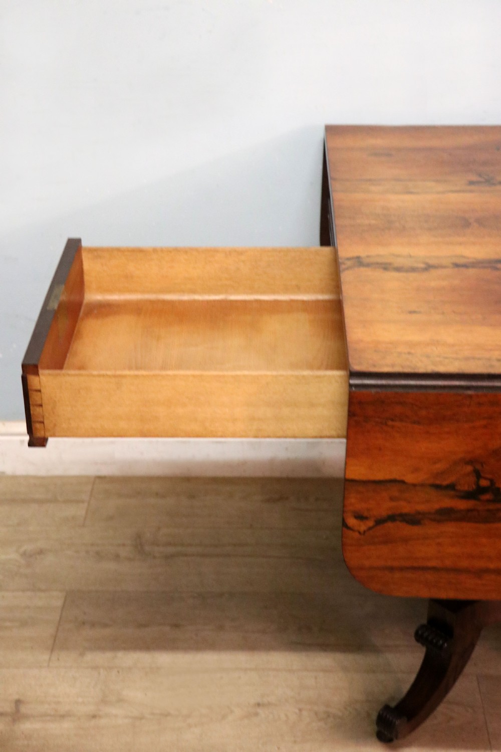 A late Georgian drop-leaf sofa table crafted from dark figured rosewood with a turned pedestal stem, two frieze drawers, and splayed quadruped legs with brass castors. View XXII