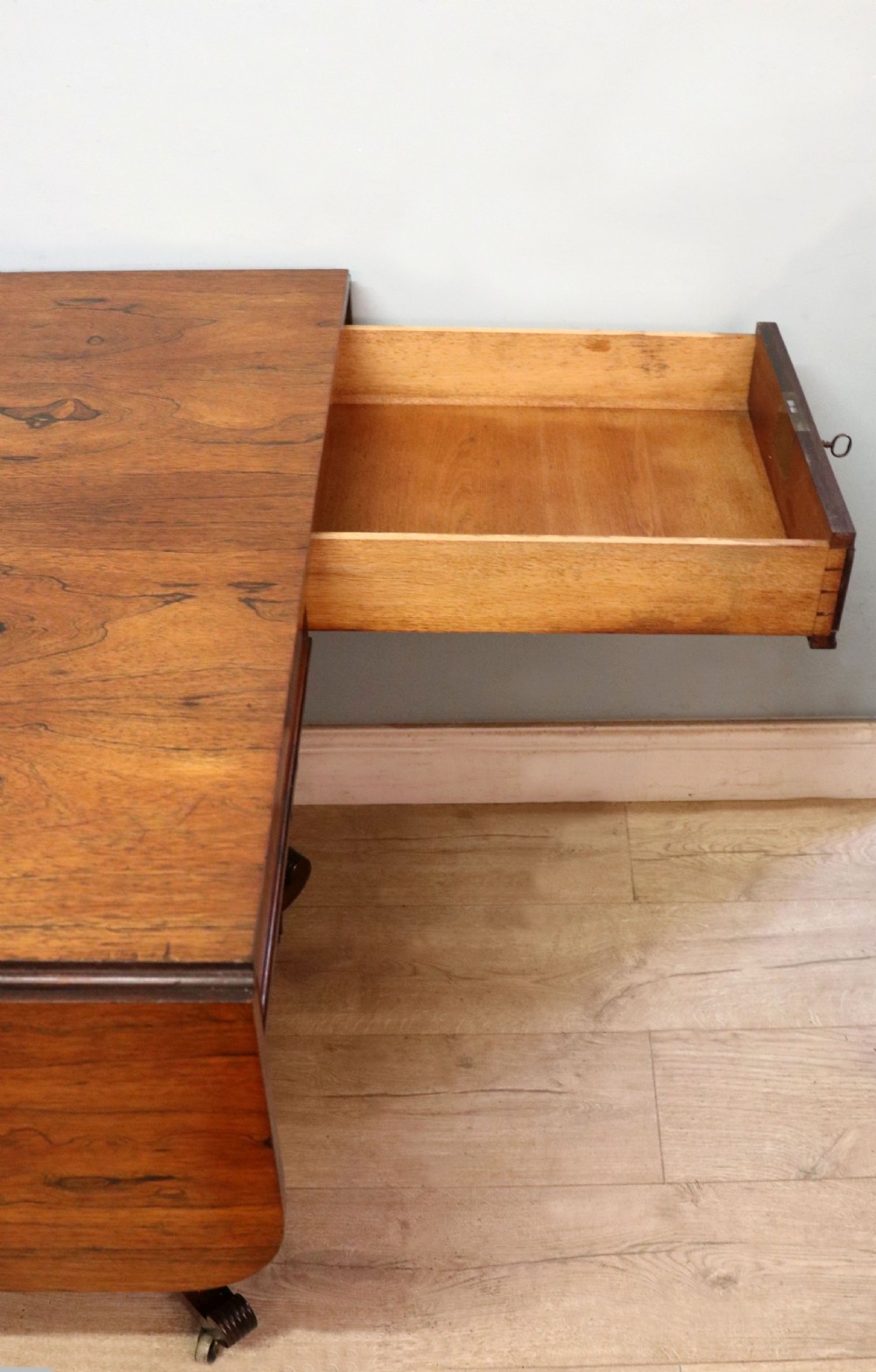 A late Georgian drop-leaf sofa table crafted from dark figured rosewood with a turned pedestal stem, two frieze drawers, and splayed quadruped legs with brass castors. View XXIII