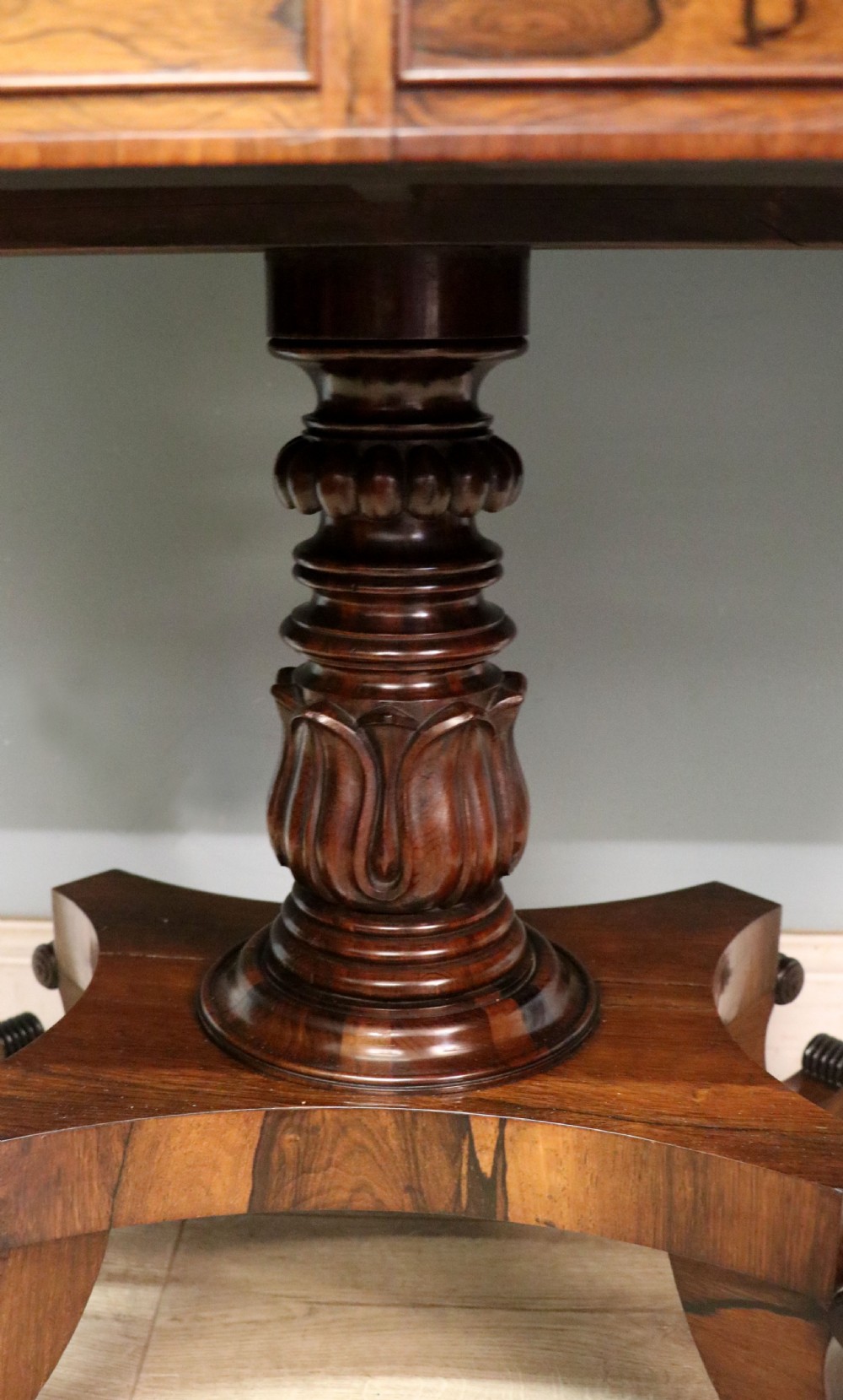 A late Georgian drop-leaf sofa table crafted from dark figured rosewood with a turned pedestal stem, two frieze drawers, and splayed quadruped legs with brass castors. View XXIV