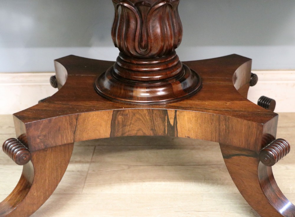 A late Georgian drop-leaf sofa table crafted from dark figured rosewood with a turned pedestal stem, two frieze drawers, and splayed quadruped legs with brass castors. View XXVI