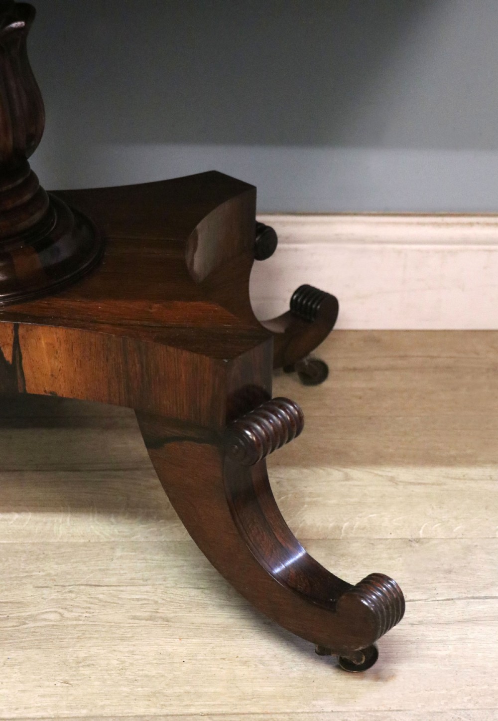 A late Georgian drop-leaf sofa table crafted from dark figured rosewood with a turned pedestal stem, two frieze drawers, and splayed quadruped legs with brass castors. View XXVII