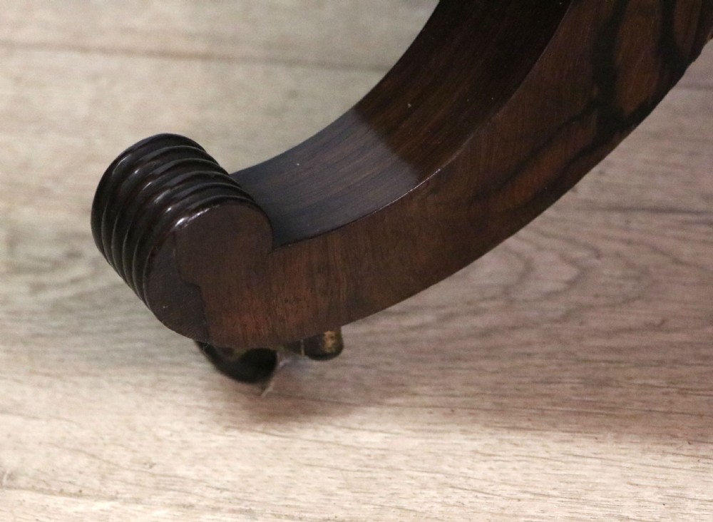 A late Georgian drop-leaf sofa table crafted from dark figured rosewood with a turned pedestal stem, two frieze drawers, and splayed quadruped legs with brass castors. View XXIX