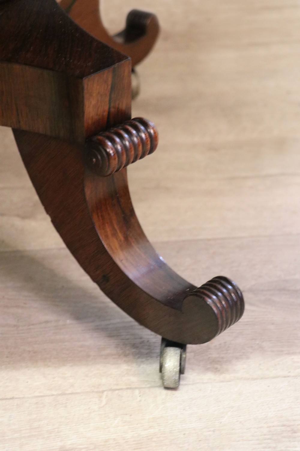 A late Georgian drop-leaf sofa table crafted from dark figured rosewood with a turned pedestal stem, two frieze drawers, and splayed quadruped legs with brass castors. View XXX
