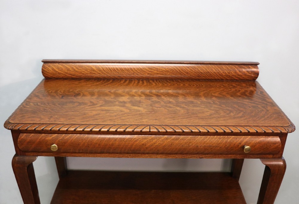 A Georgian revival oak side table featuring a single drawer with brass knobs, a lower tier shelf, and cabriole legs terminating in carved claw and ball feet. View II