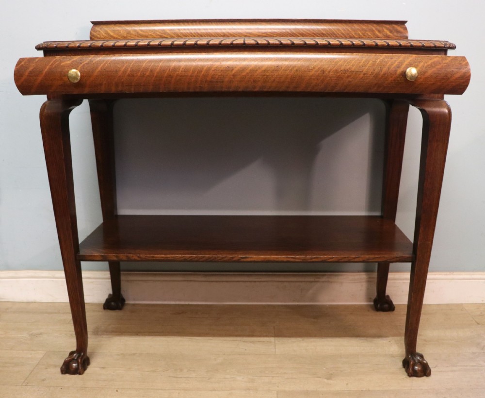 A Georgian revival oak side table featuring a single drawer with brass knobs, a lower tier shelf, and cabriole legs terminating in carved claw and ball feet. View IV