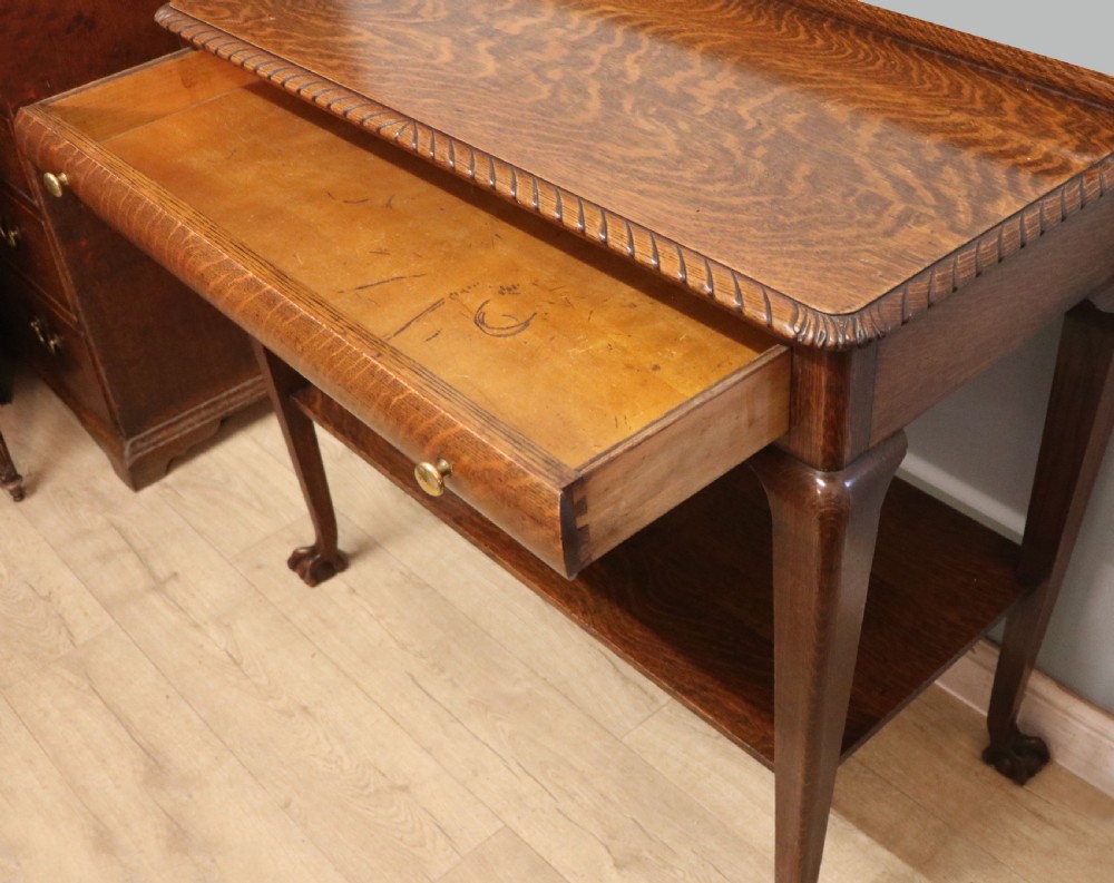 A Georgian revival oak side table featuring a single drawer with brass knobs, a lower tier shelf, and cabriole legs terminating in carved claw and ball feet. View V