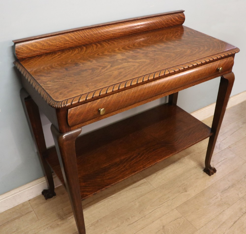 A Georgian revival oak side table featuring a single drawer with brass knobs, a lower tier shelf, and cabriole legs terminating in carved claw and ball feet. View VI