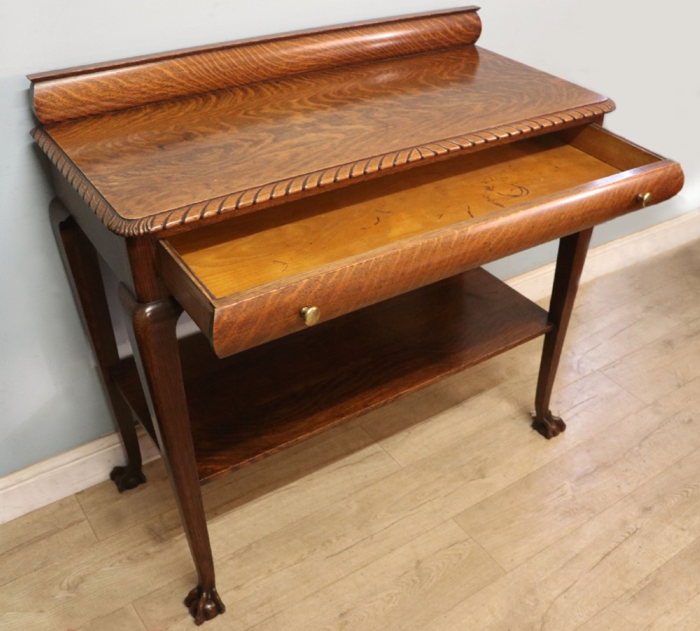 A Georgian revival oak side table featuring a single drawer with brass knobs, a lower tier shelf, and cabriole legs terminating in carved claw and ball feet. View VII