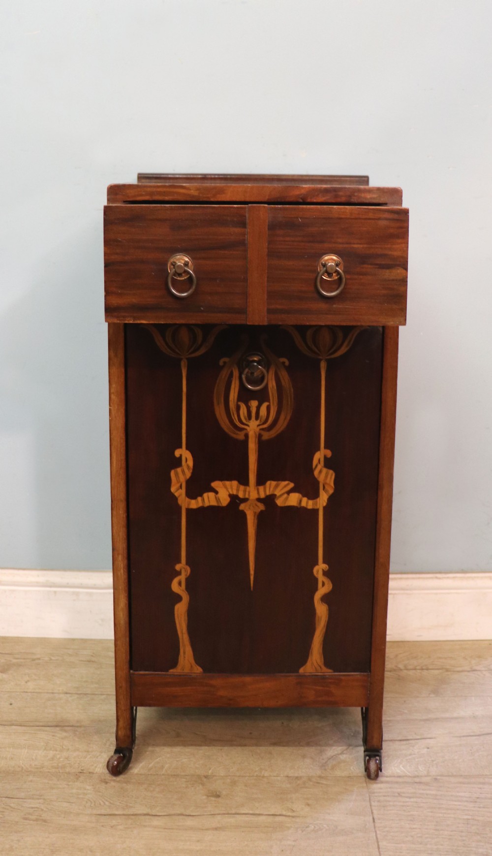 A tall dark wood Art Nouveau coal box featuring botanical marquetry inlay and brass ring handles, supported on castors. View IV