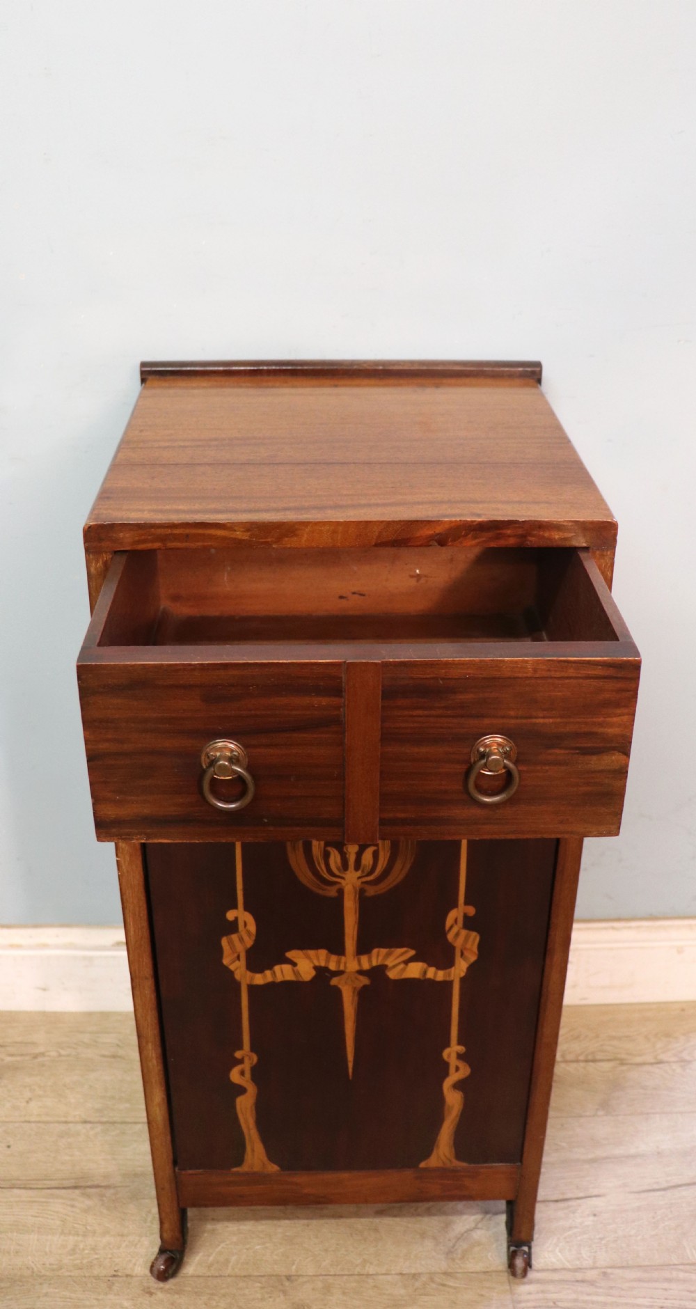 A tall dark wood Art Nouveau coal box featuring botanical marquetry inlay and brass ring handles, supported on castors. View V