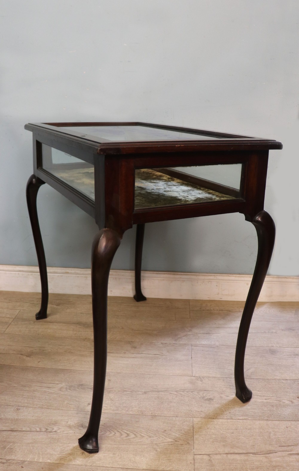 A dark mahogany glazed bijouterie table featuring cabriole legs, a glass top with blue Breitling watch branding, and a lined interior display compartment. View VII