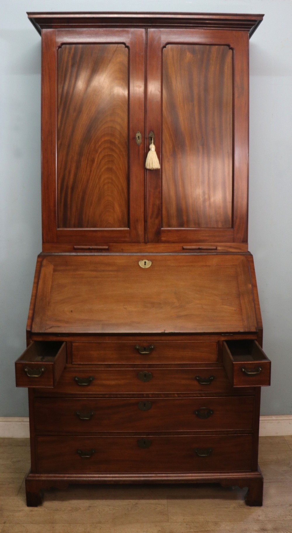 A George III mahogany bureau bookcase featuring a panelled upper cabinet above a fall-front writing surface and graduated drawers with brass hardware. View IV