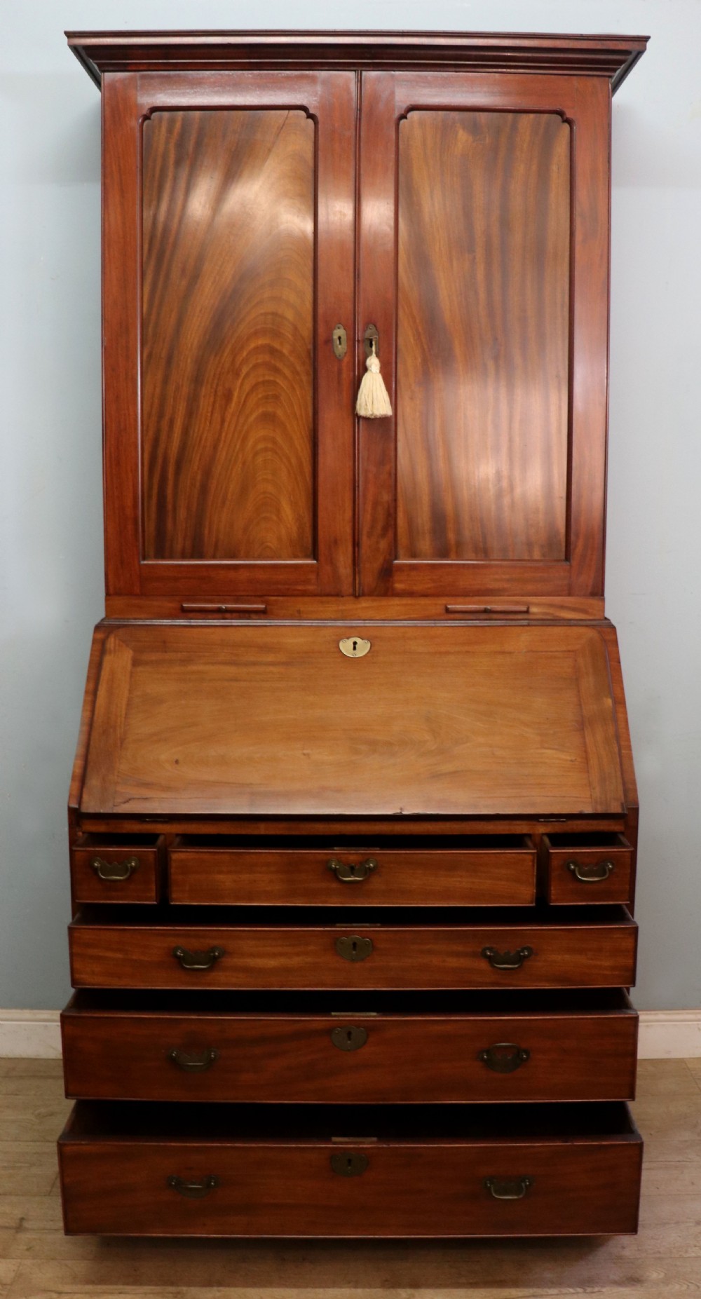 A George III mahogany bureau bookcase featuring a panelled upper cabinet above a fall-front writing surface and graduated drawers with brass hardware. View V