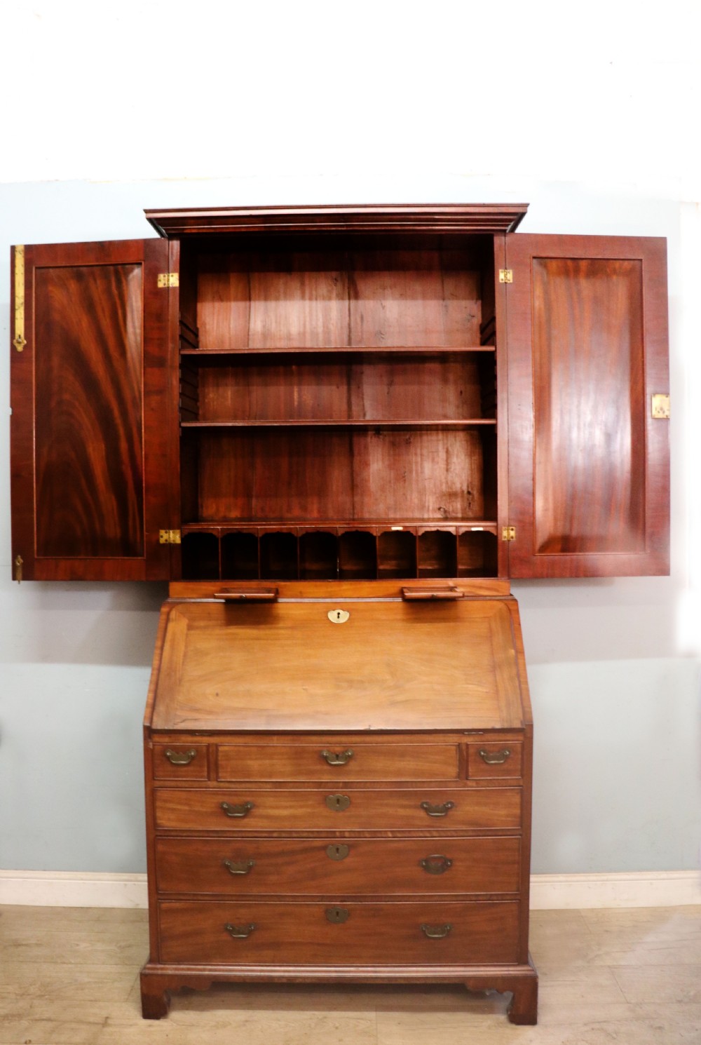 A George III mahogany bureau bookcase featuring a panelled upper cabinet above a fall-front writing surface and graduated drawers with brass hardware. View VII