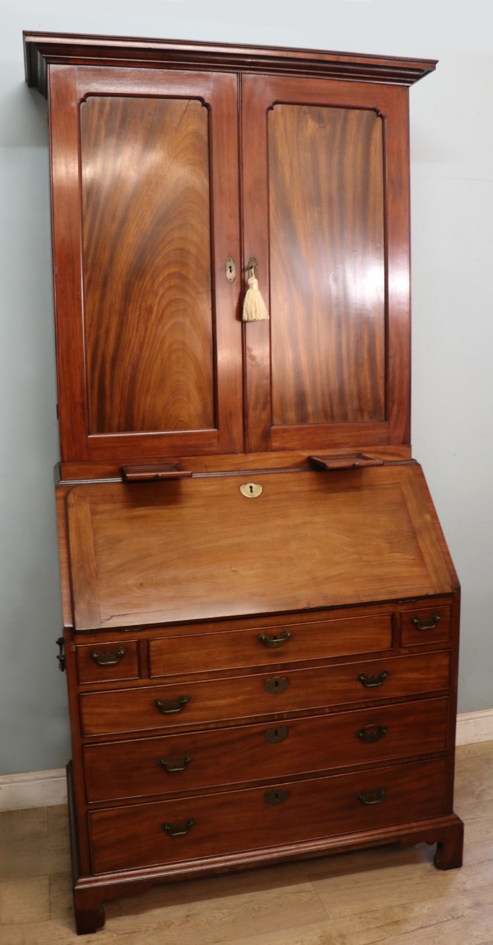 A George III mahogany bureau bookcase featuring a panelled upper cabinet above a fall-front writing surface and graduated drawers with brass hardware. View VIII
