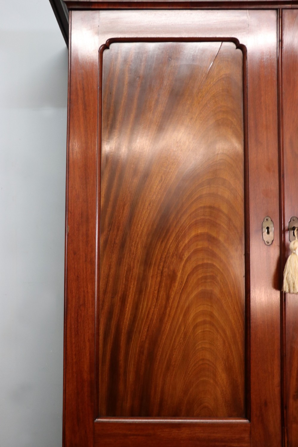 A George III mahogany bureau bookcase featuring a panelled upper cabinet above a fall-front writing surface and graduated drawers with brass hardware. View X