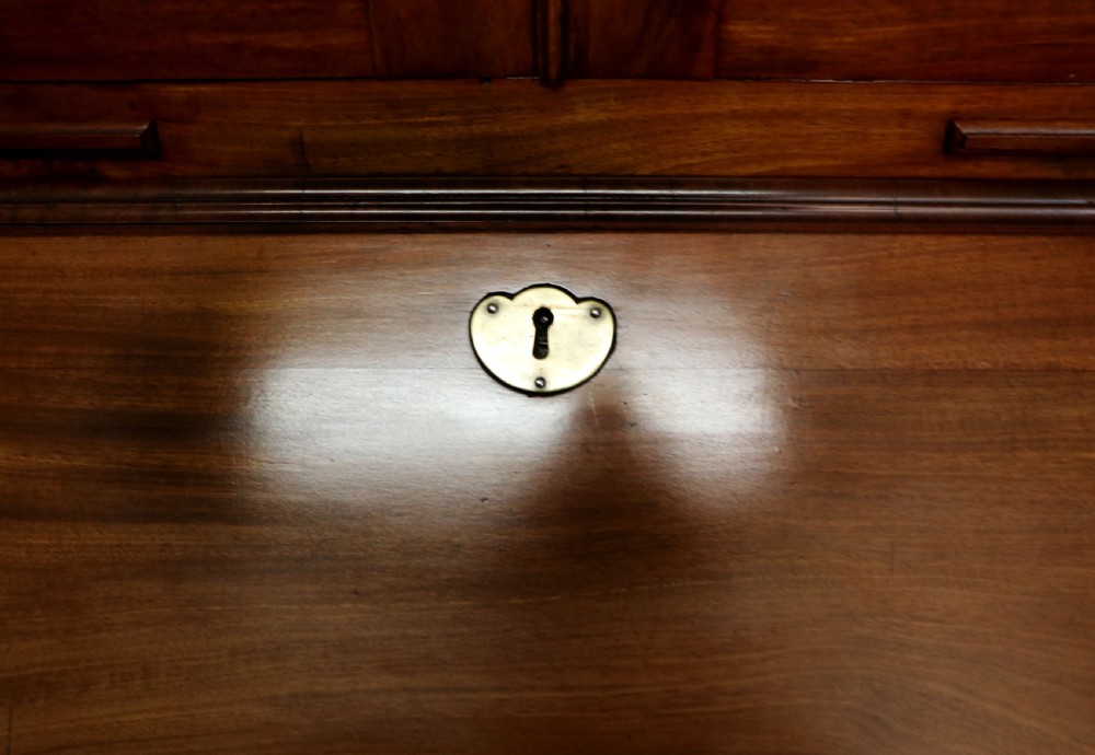 A George III mahogany bureau bookcase featuring a panelled upper cabinet above a fall-front writing surface and graduated drawers with brass hardware. View XVIII