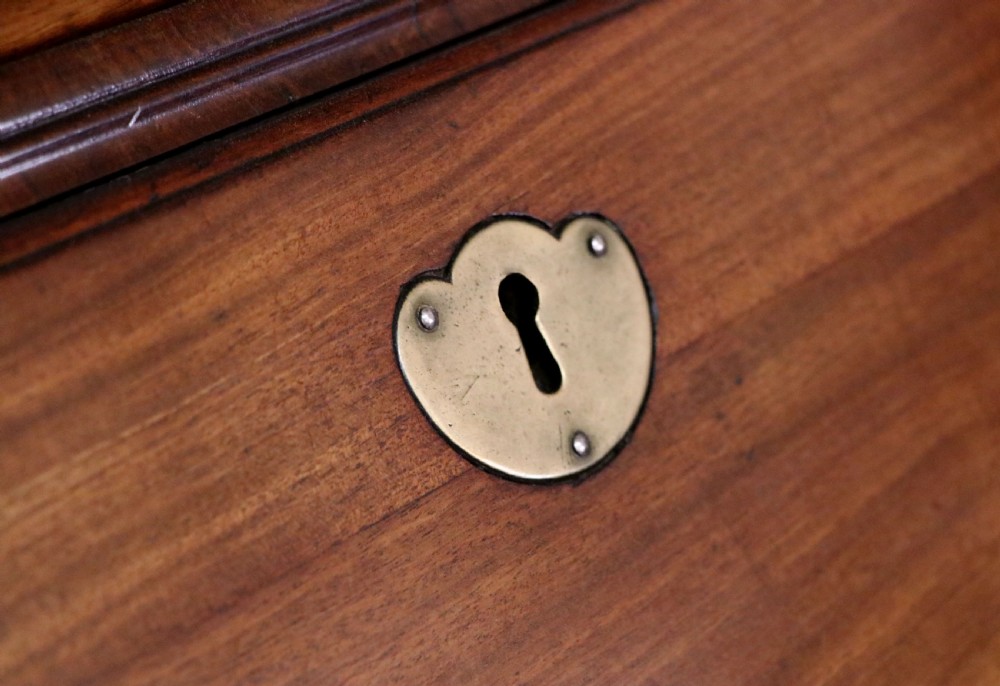 A George III mahogany bureau bookcase featuring a panelled upper cabinet above a fall-front writing surface and graduated drawers with brass hardware. View XX