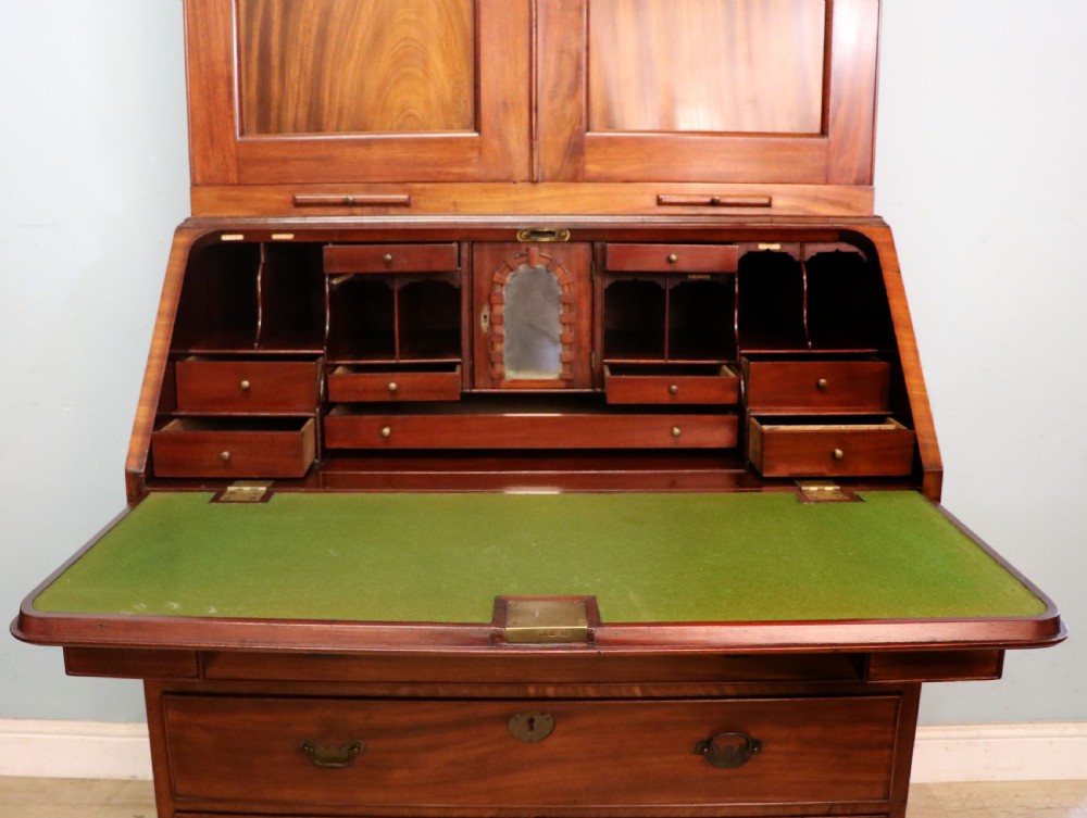 A George III mahogany bureau bookcase featuring a panelled upper cabinet above a fall-front writing surface and graduated drawers with brass hardware. View XXIII