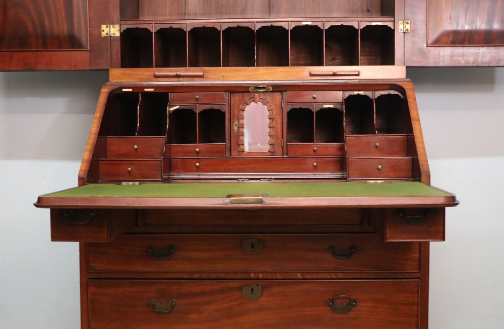 A George III mahogany bureau bookcase featuring a panelled upper cabinet above a fall-front writing surface and graduated drawers with brass hardware. View XXVIII
